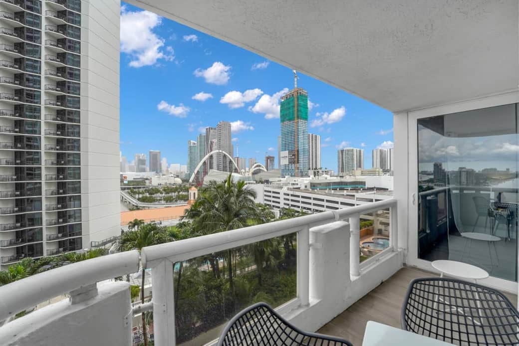 Private balcony with access from living room and first bedroom. Seating for 4 at outdoor dining table. Views of Miami Skyline and Biscayne Bay water views.