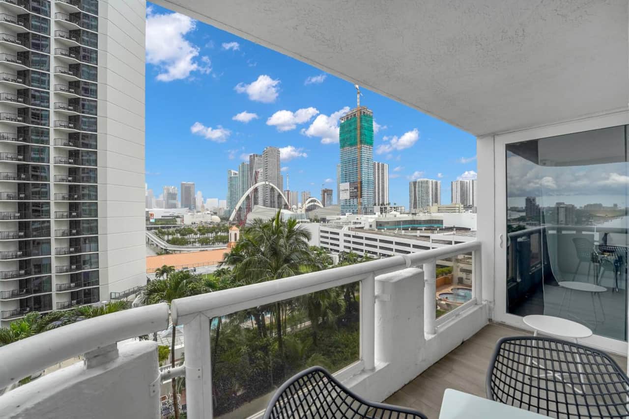 Private balcony with access from living room and first bedroom. Seating for 4 at outdoor dining table. Views of Miami Skyline and Biscayne Bay water views.
