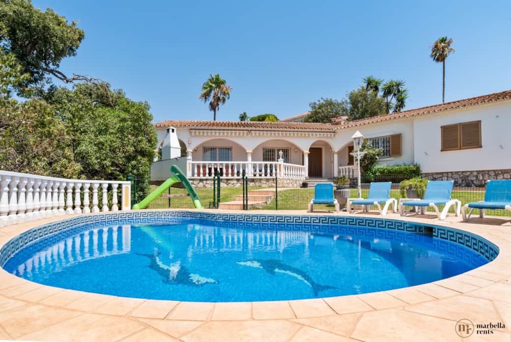 Fully fenced pool with sun loungers.