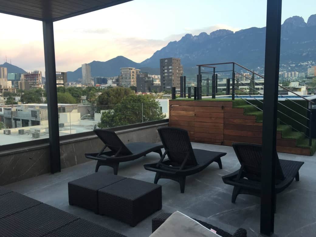 Área de rooftop con camastros bajo pérgola