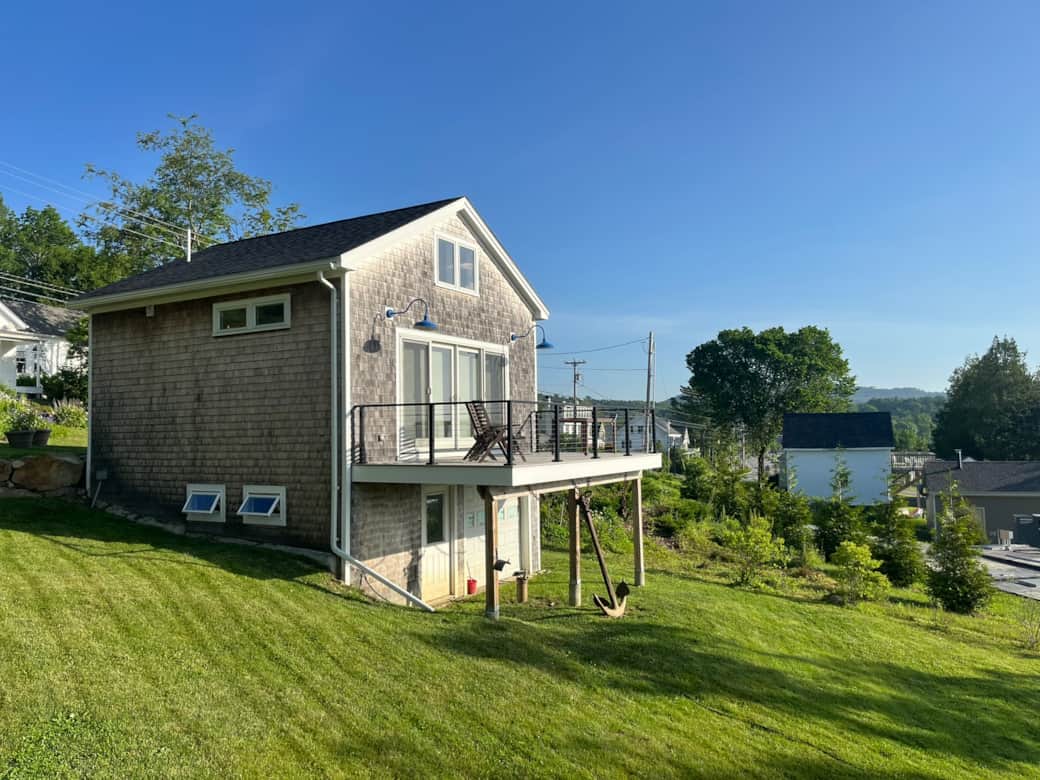 Rustic cedar cottage with deck, barn lights & big windows—charm meets modern style.