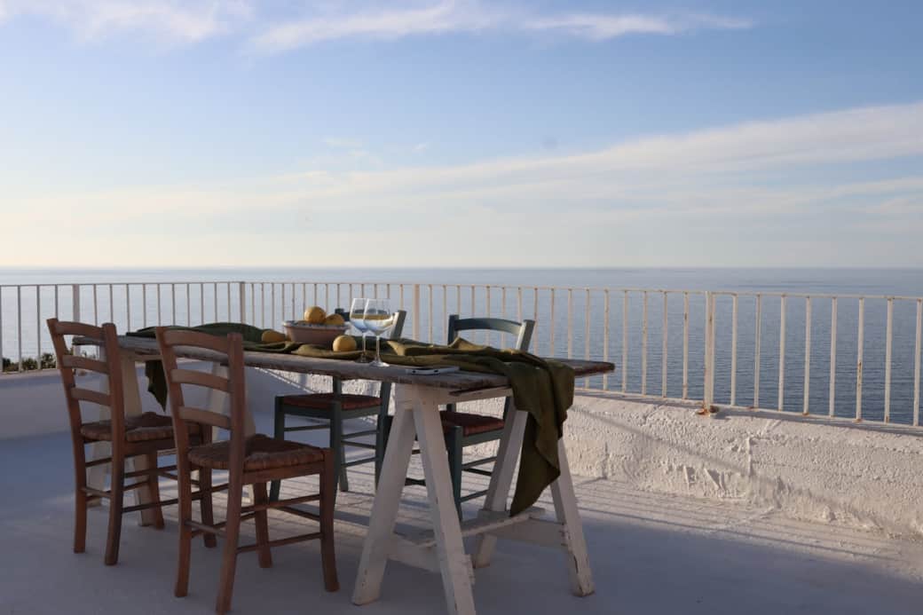 Gusta i sapori locali sul tavolo in terrazza con l'azzurro del mare di Salina all'orizzonte.