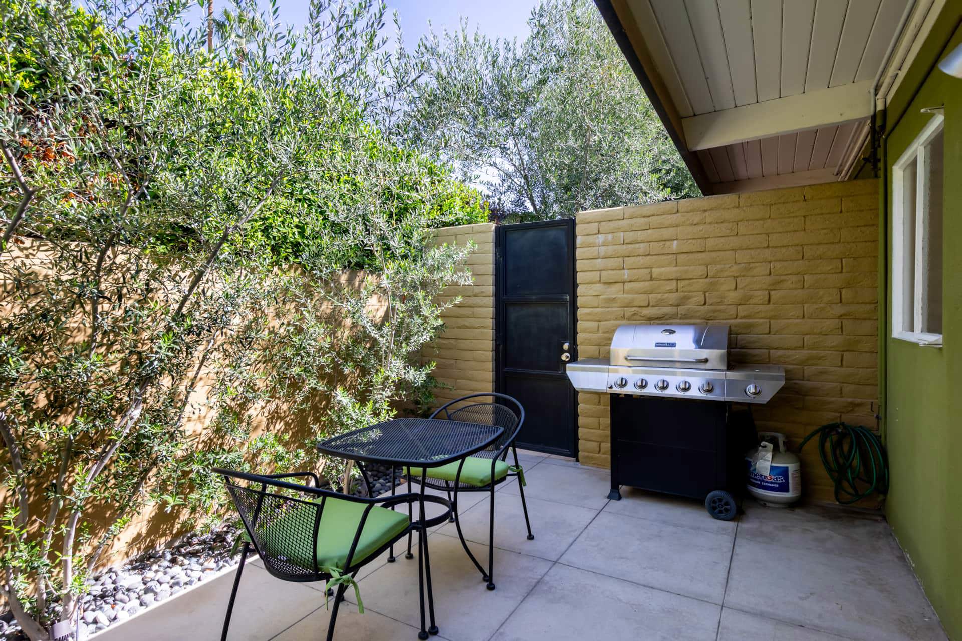 A patio with a grill, table, and chairs