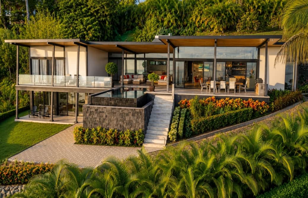 A stunning aerial perspective showcasing the villa’s striking architecture, infinity pool, lush tropical gardens, and seamless indoor-outdoor living—bathed in the warm glow of Costa Rica’s golden hour.