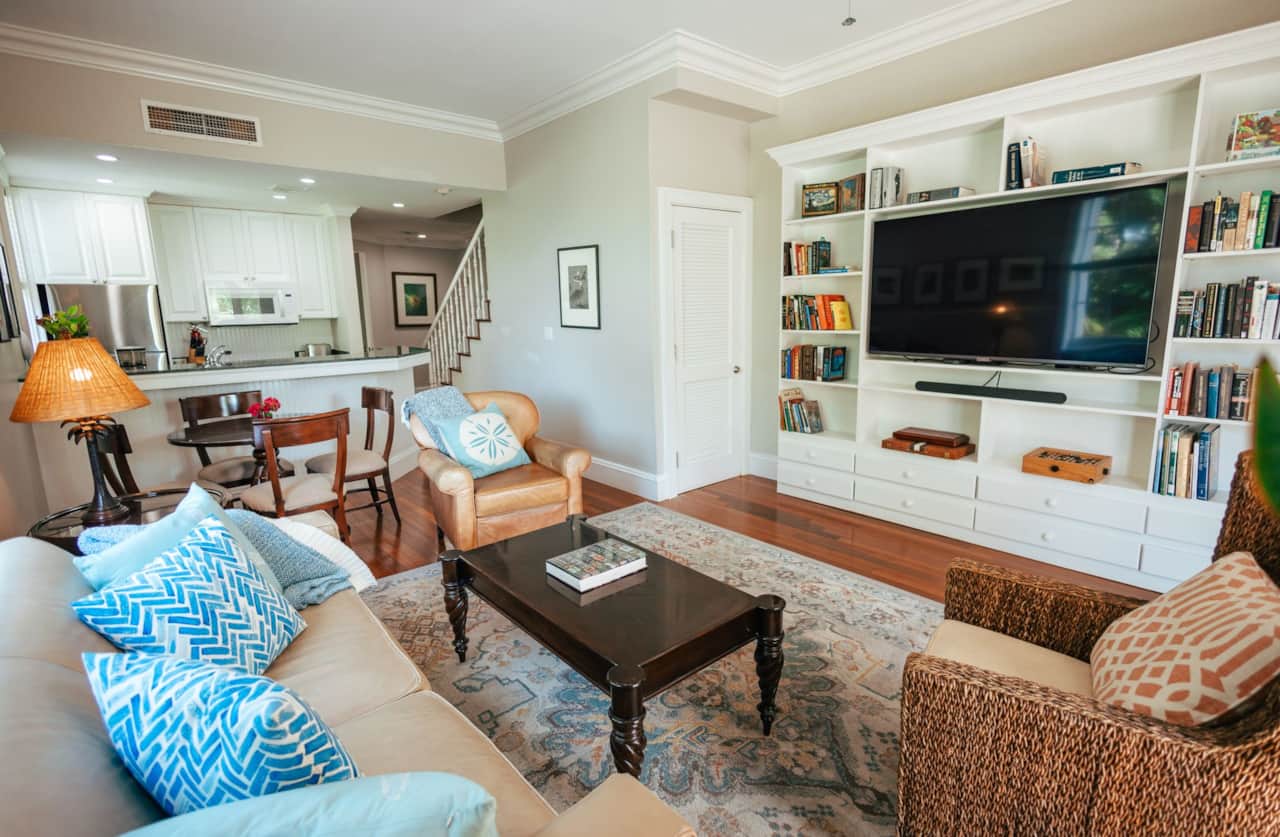 Open living room with built-in bookshelves and flat-screen TV, flowing into the kitchen open plan
