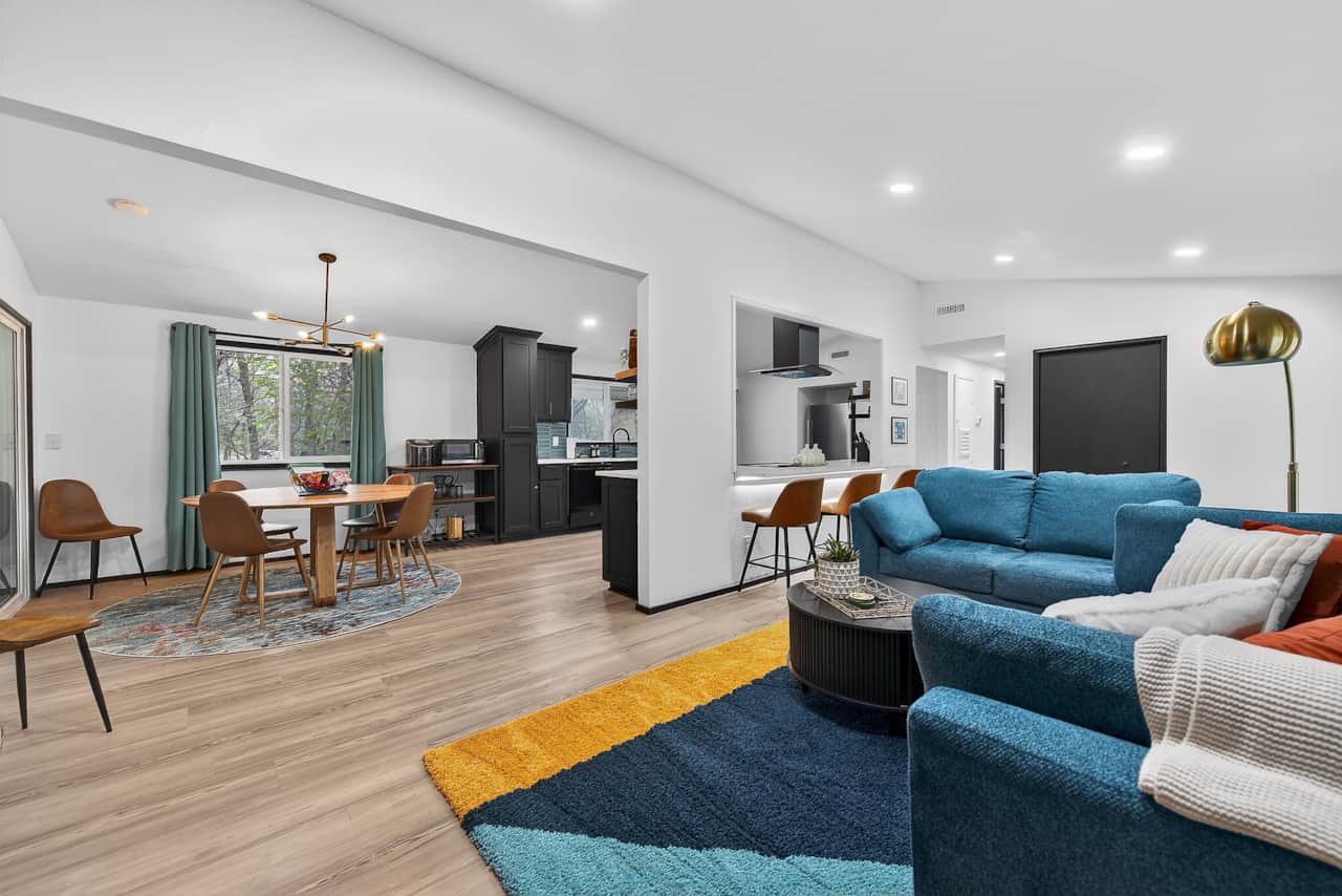 Modern Open Concept Living Space with comfy sofa, fireplace, and TV, flowing into kitchen and dining
