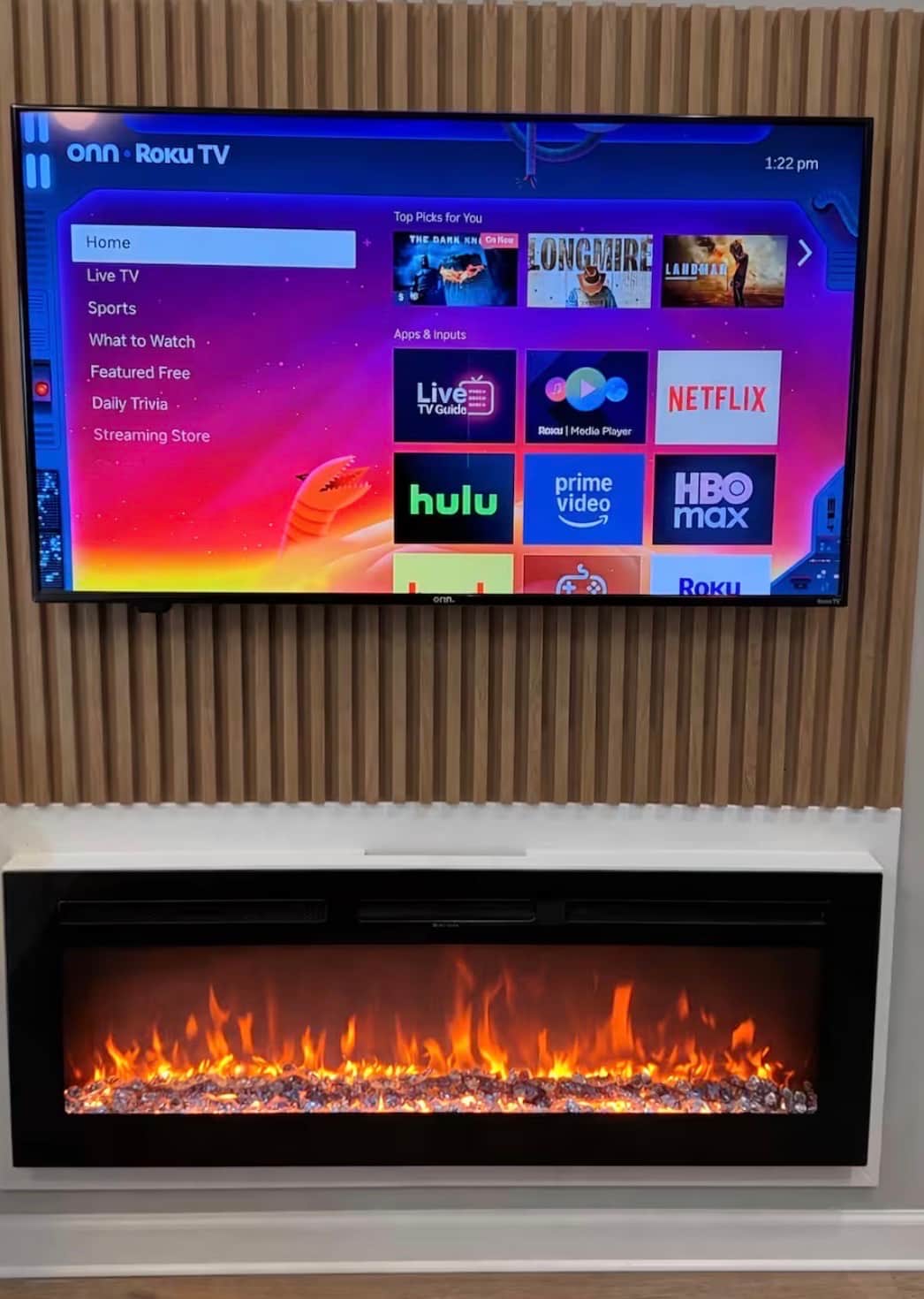 Stylish  living space featuring two futon sofa beds, a flat-screen TV, and a modern electric fireplace. The large island bar offers generous seating and flows into the kitchen, creating a comfortable space to relax, dine, or entertain.