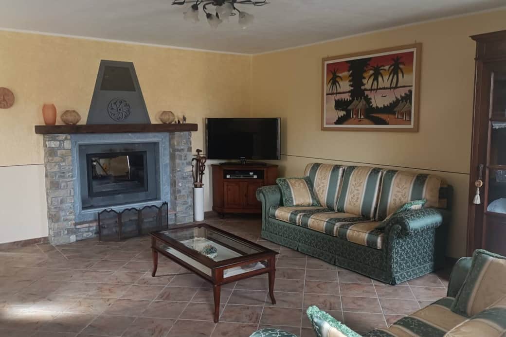 Salotto fornito di doppio divano, caminetto, TV con decoder satellitare. 