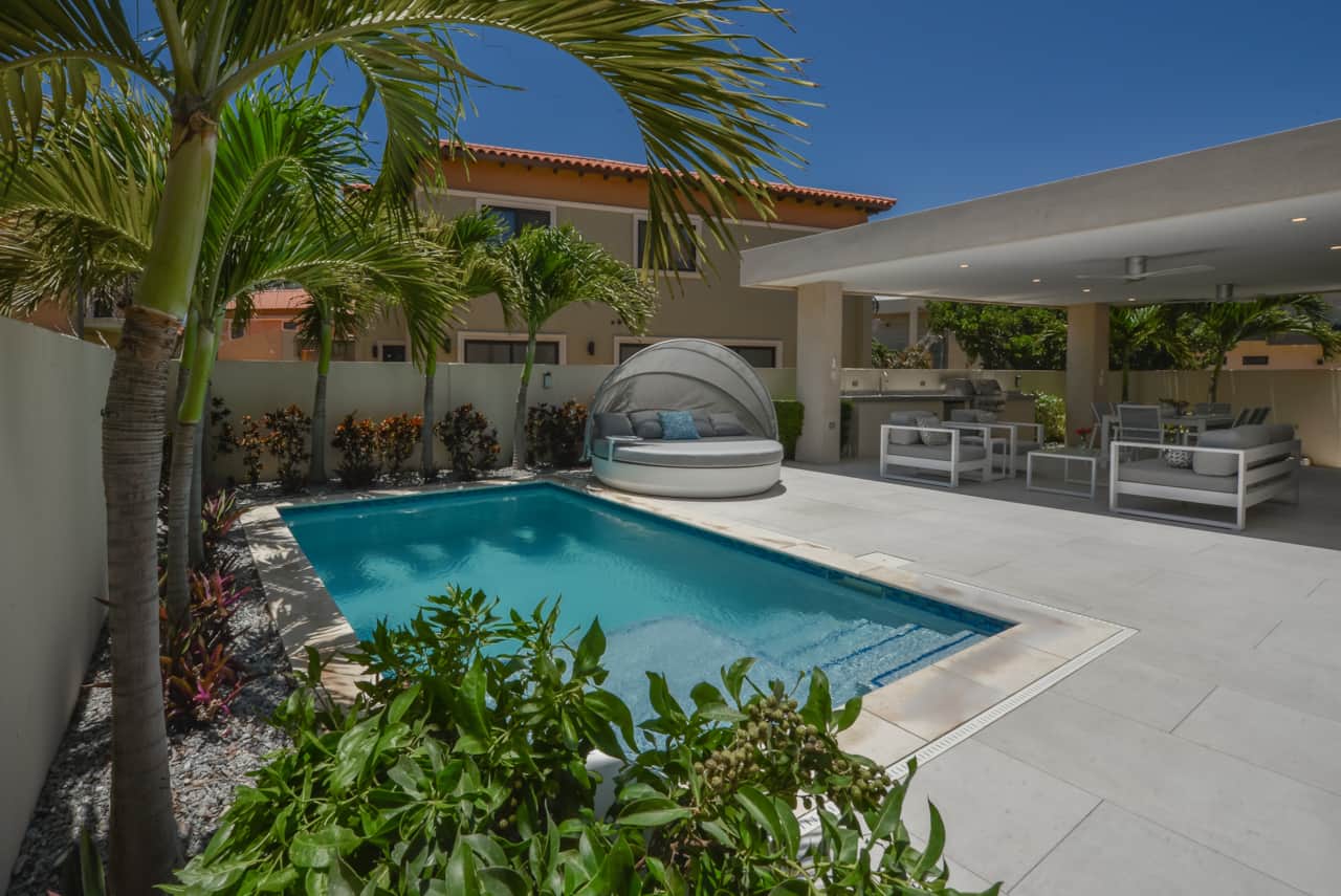 Backyard with private pool, daybed for lounging poolside, and gazebo-covered dining & lounging areas