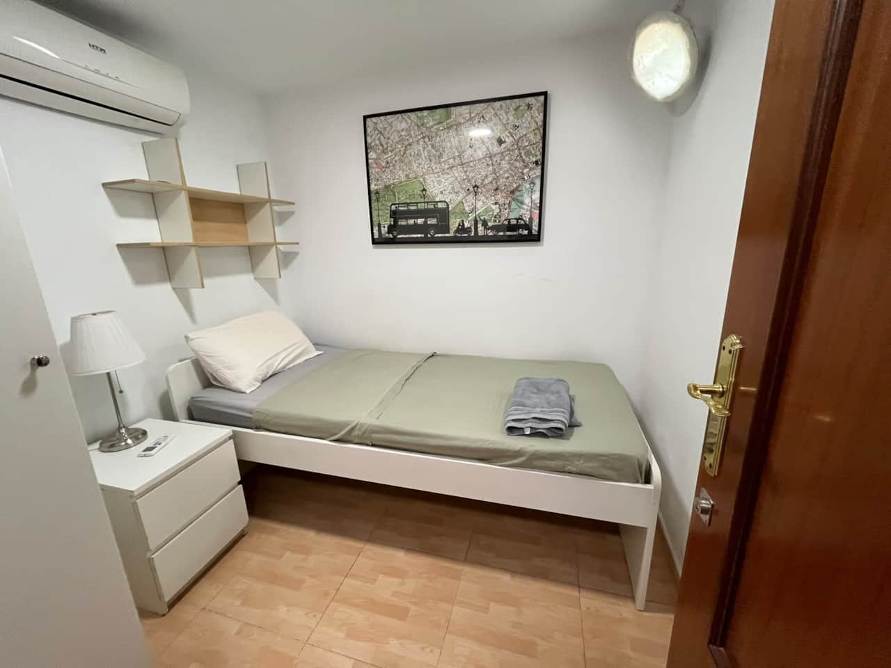 Single bedroom with bedside table, shelves and air conditioning