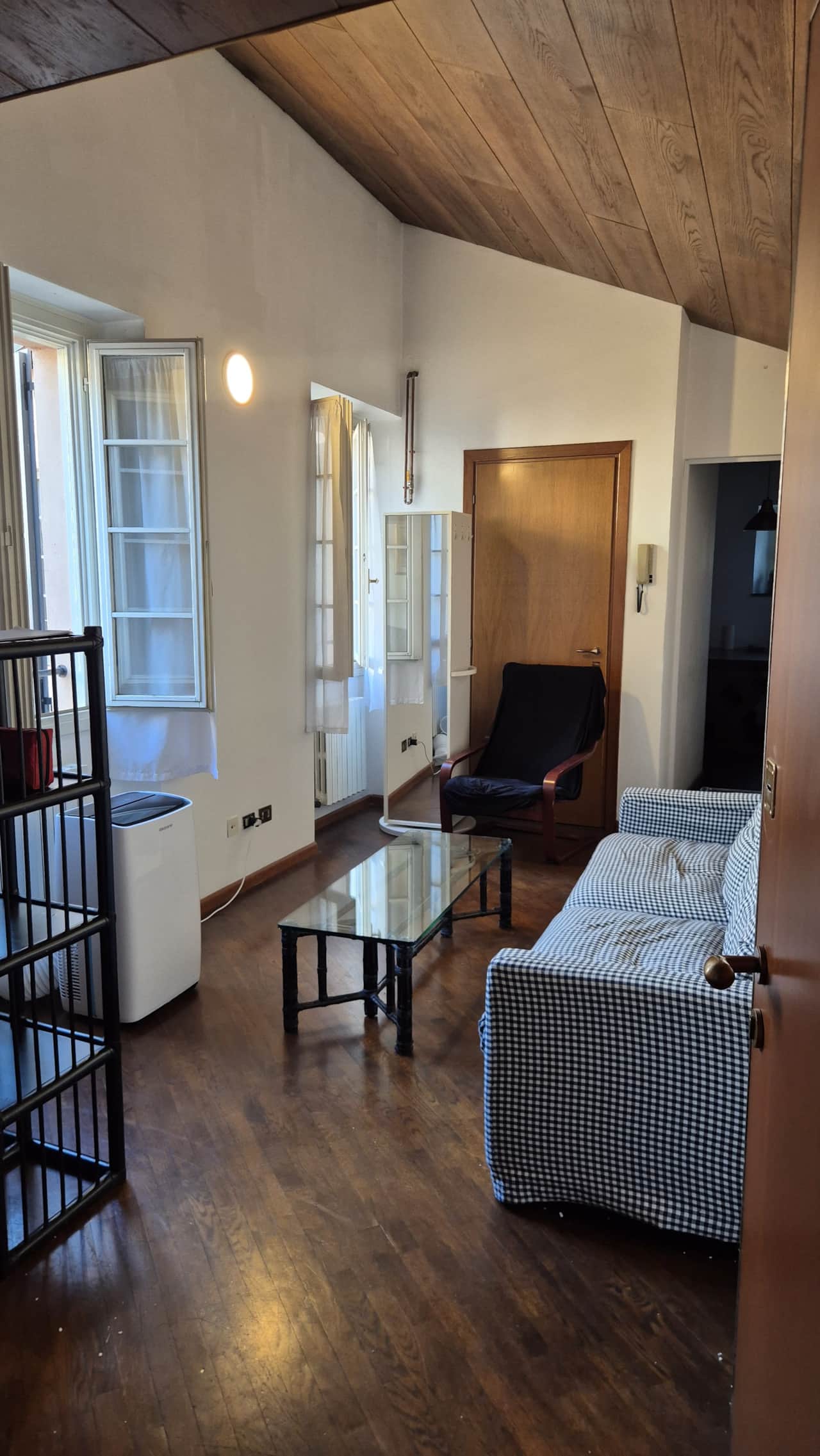 Salón abuhardillado con sofá cama y techo con vigas, en el casco antiguo de Como