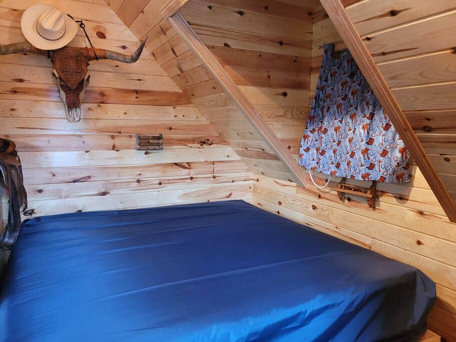 King bed upstairs, air conditioner unit behind curtain.