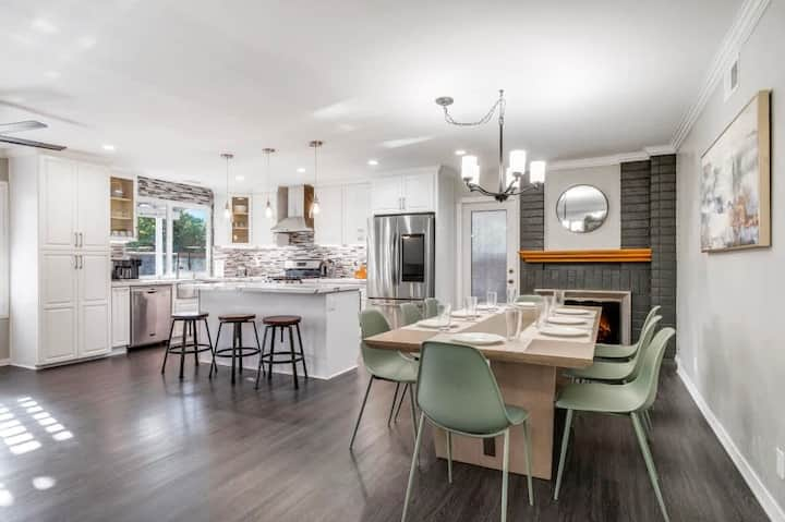 Open kitchen and dining space with island seating and a welcoming fireplace.