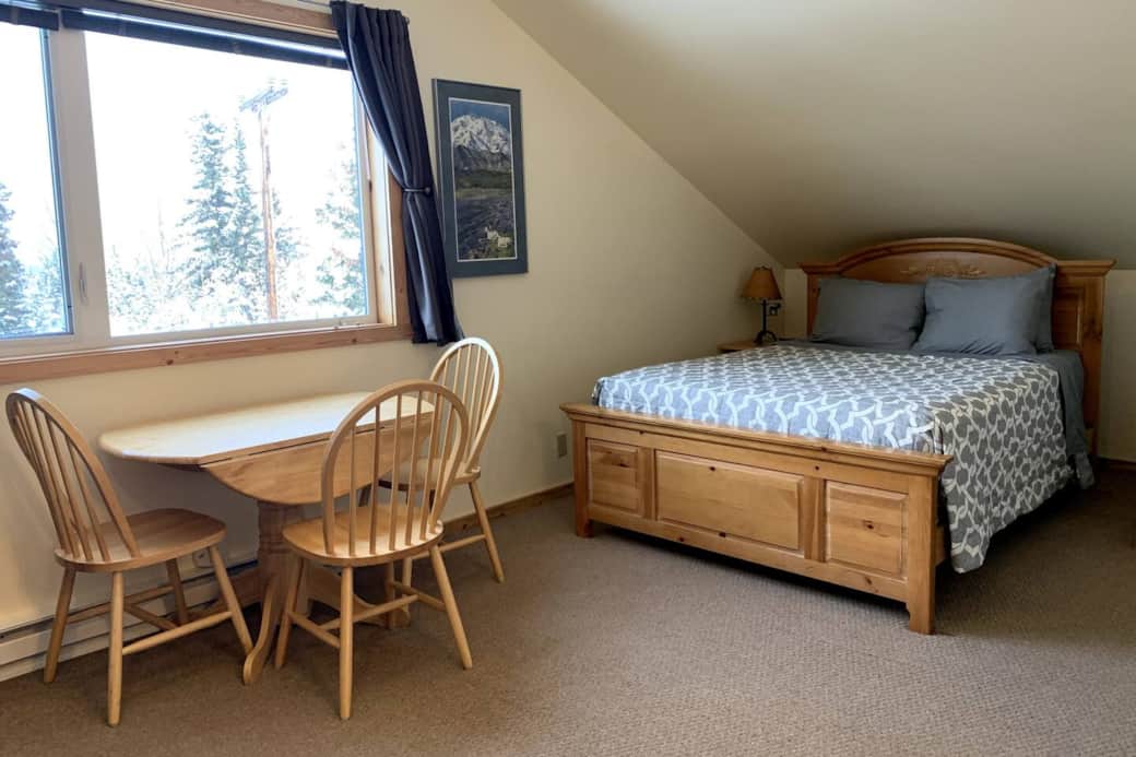 Queen bed and kitchen table with large bay window with mountain views.
