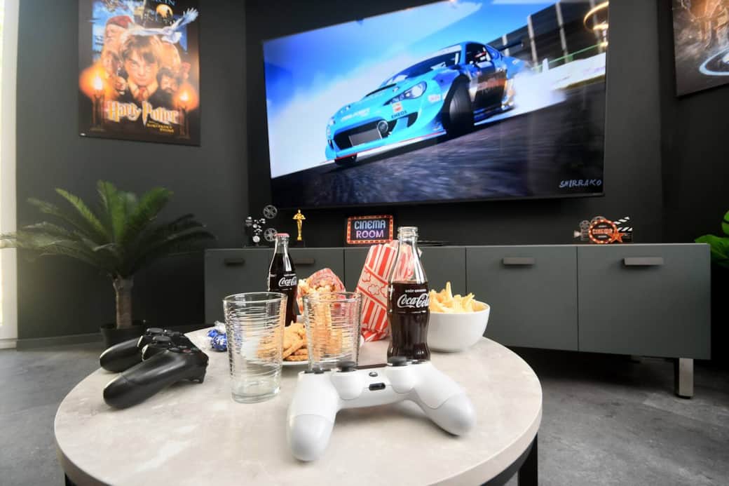 Salon immersif avec grand écran et espace repas convivial.
