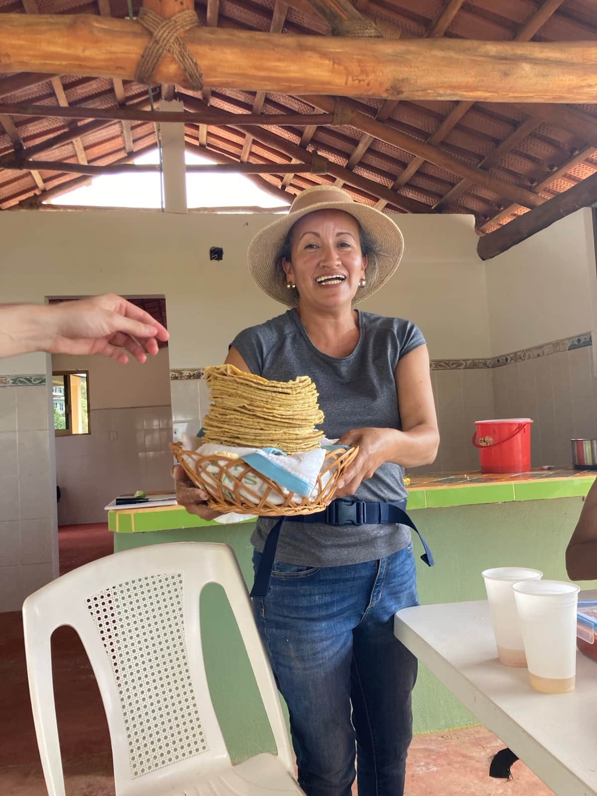 Tomasa smiling and holding a stack of fresh handmade tortillas