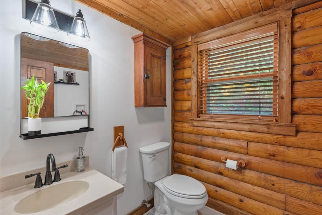 Convenient half bath with rustic log accents and direct access to laundry area, perfect for quick refreshes during longer stays.