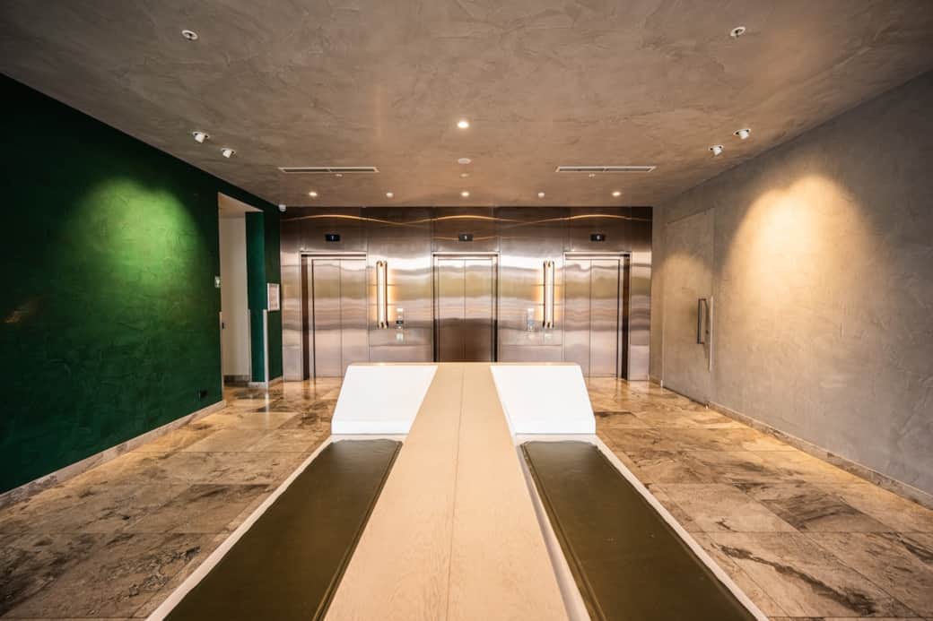 The polished, mirror-like surfaces of an apartment lobby reflect the symmetry of its modern design.