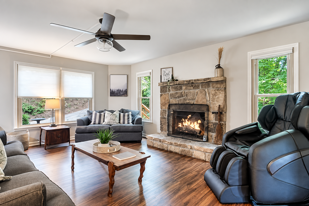 Bright, comfortable living room with a cozy stone fireplace and woodland view