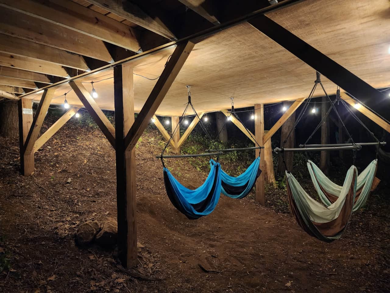 Cabin 3 hammock swings at night with cafe lights on.