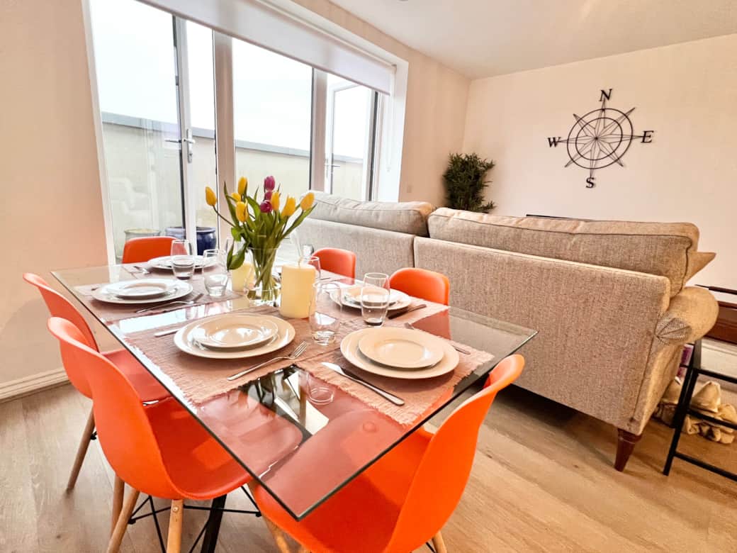 Bright and inviting space with vibrant chairs and a table for six, perfect for meals and laughter.