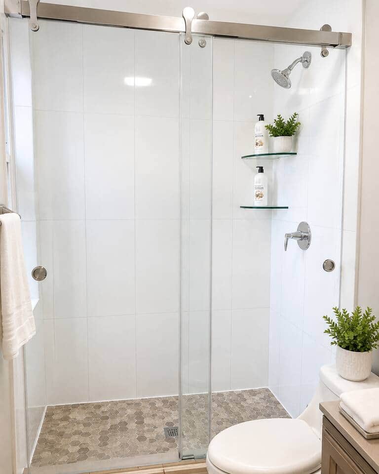 Clean and modern bathroom featuring a refreshing shower, illuminated vanity mirror, spacious sink, fresh towels, and convenient storage—perfect for getting ready or unwinding after a long day
