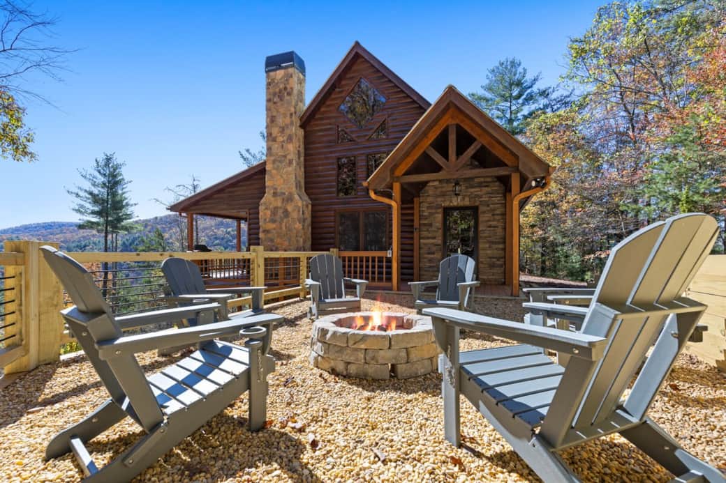 A cozy firepit with six Adirondack chairs, each with cup holders, arranged in a welcoming circle—perfect for relaxing and enjoying the outdoors.