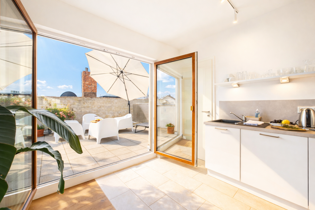 Heller, moderner Wohnraum mit offener Küche und direktem Zugang zur sonnigen Dachterrasse. Heller, moderner Wohnraum mit offener Küche und direktem Zugang zur sonnigen Dachterrasse.