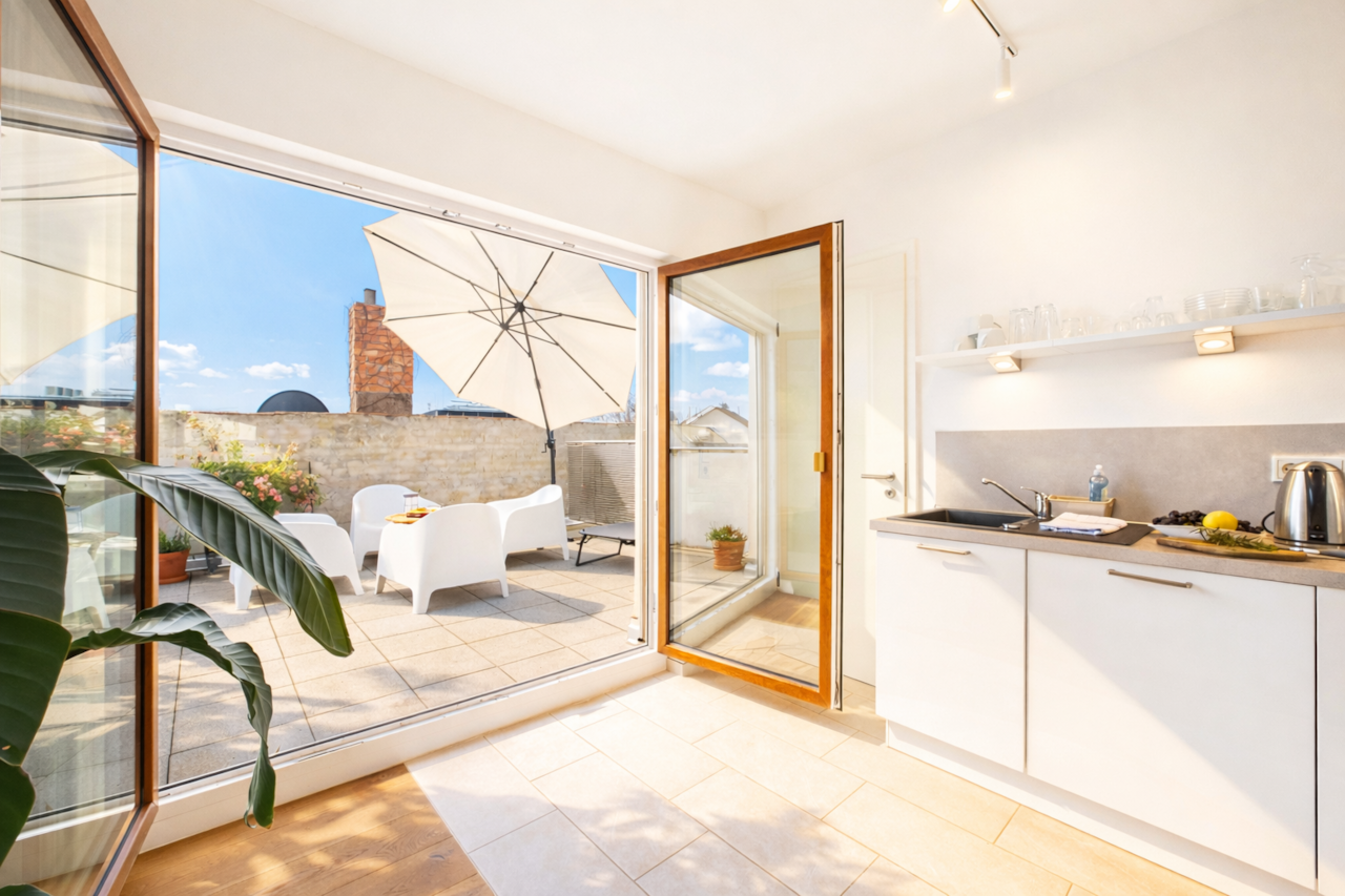 Heller, moderner Wohnraum mit offener Küche und direktem Zugang zur sonnigen Dachterrasse.