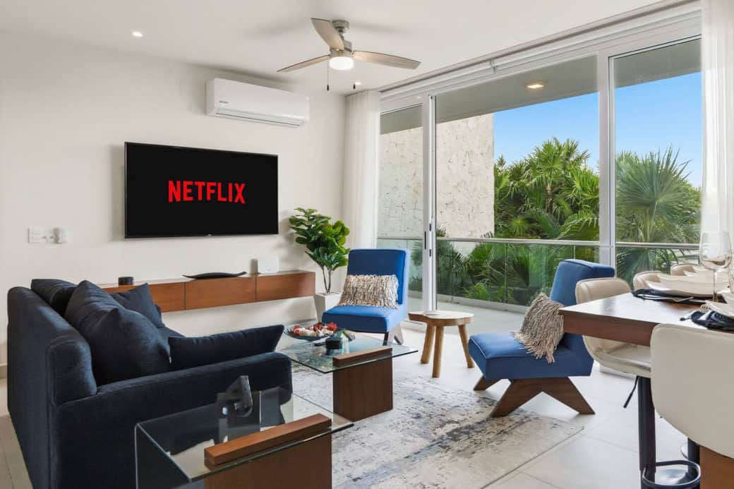 A welcoming living room featuring a comfortable sofa bed, large smart TV, and wide sliding glass doors that open to a private balcony with lush jungle and pool views. A perfect spot to relax, stream your favorites, and enjoy the scenery. A welcoming living room featuring a comfortable sofa bed, large smart TV, and wide sliding glass doors that open to a private balcony with lush jungle and pool views. A perfect spot to relax, stream your favorites, and enjoy the scenery.