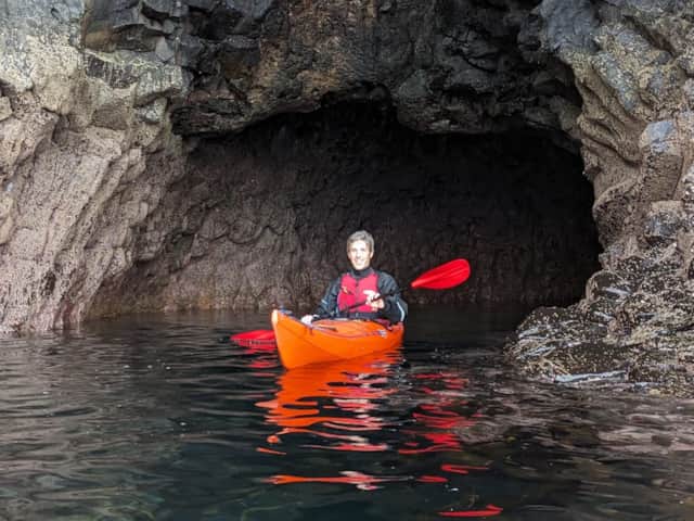 Kayaker exploring a sea cave with Bendoran Watersports