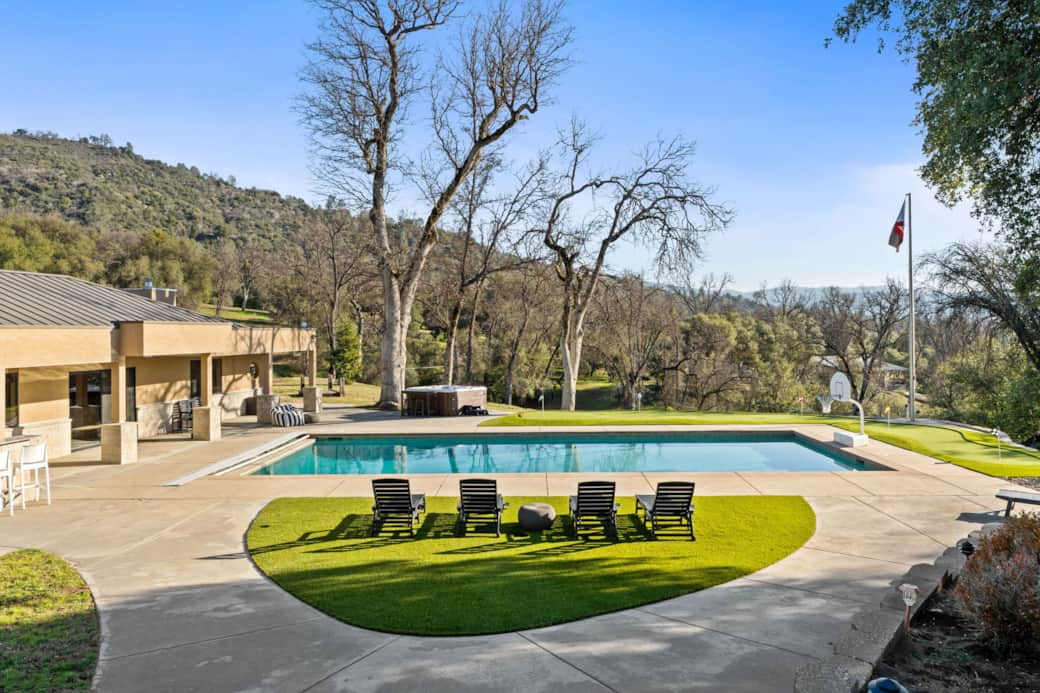 Oversized outdoor pool with a basketball hoop, sun loungers and a spa - set against mountains