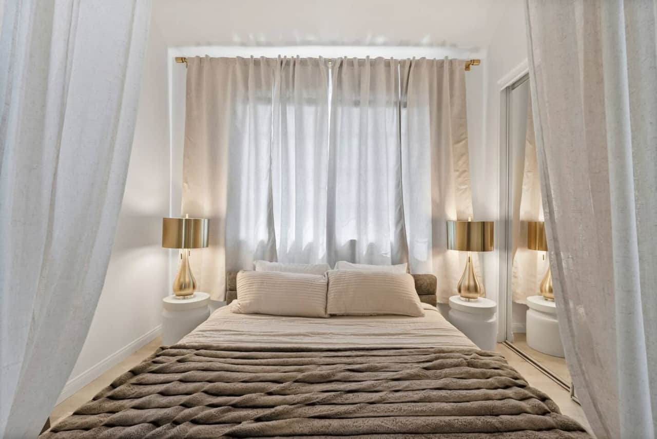 Serene bedroom retreat featuring a plush queen bed draped in soft curtains.