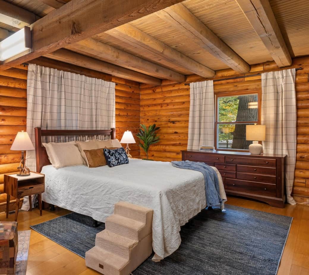 Warm and inviting primary bedroom featuring a king bed, log walls, exposed beams, and a sitting area for peaceful views - perfect for a restful night's sleep!