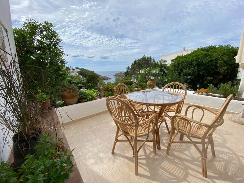 Outdoor terrace seating with garden and sea view in Cala Vadella Ibiza apartment