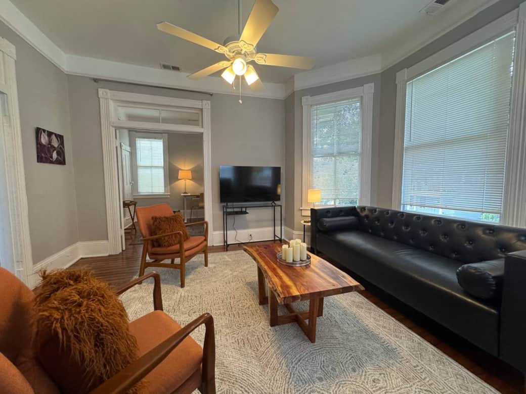 The living room offers a stylish leather couch and three additional chairs, providing comfortable seating for up to four guests. A flat-screen TV is available for streaming your favorite shows.
