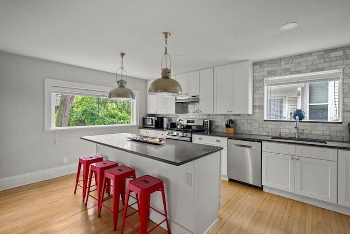 Bright, modern kitchen with stainless steel appliances, spacious island seating, and stylish pendant