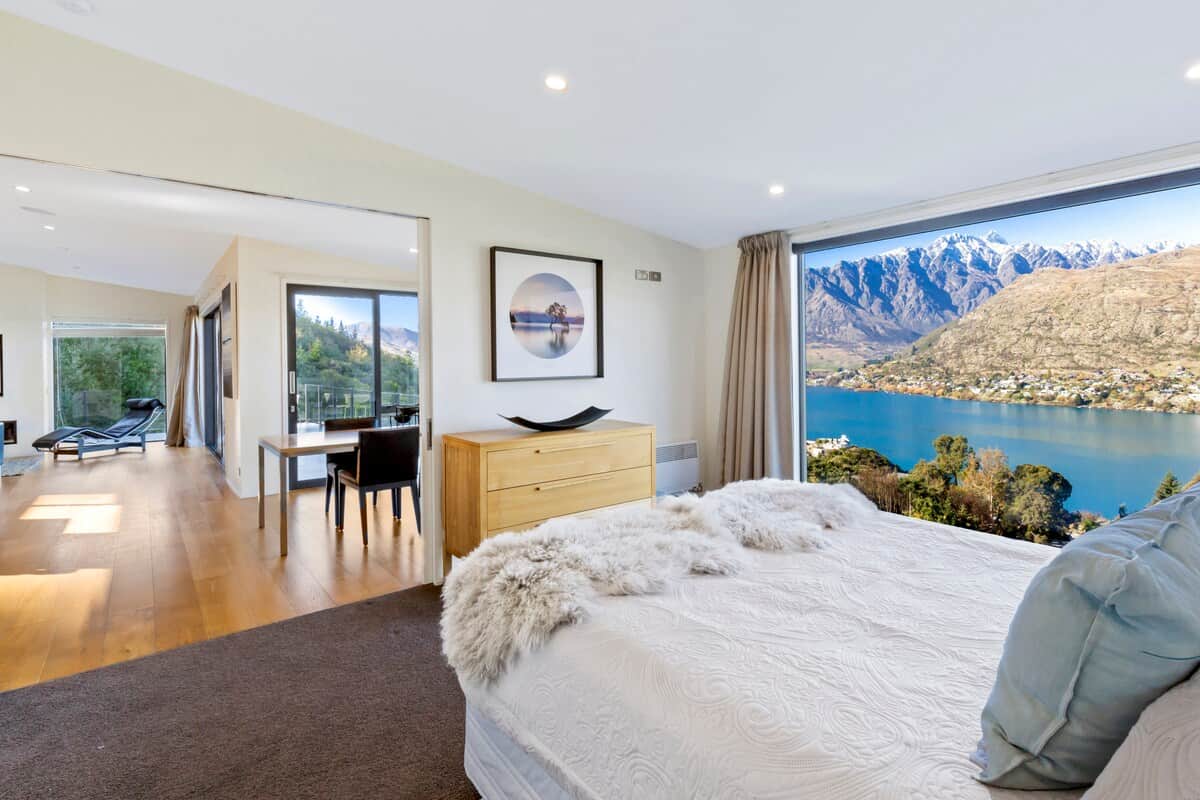Master bedroom with unobstructed lake and mountain views through the floor to ceiling window. Cavity sliding doors provide privacy to the living and dining area