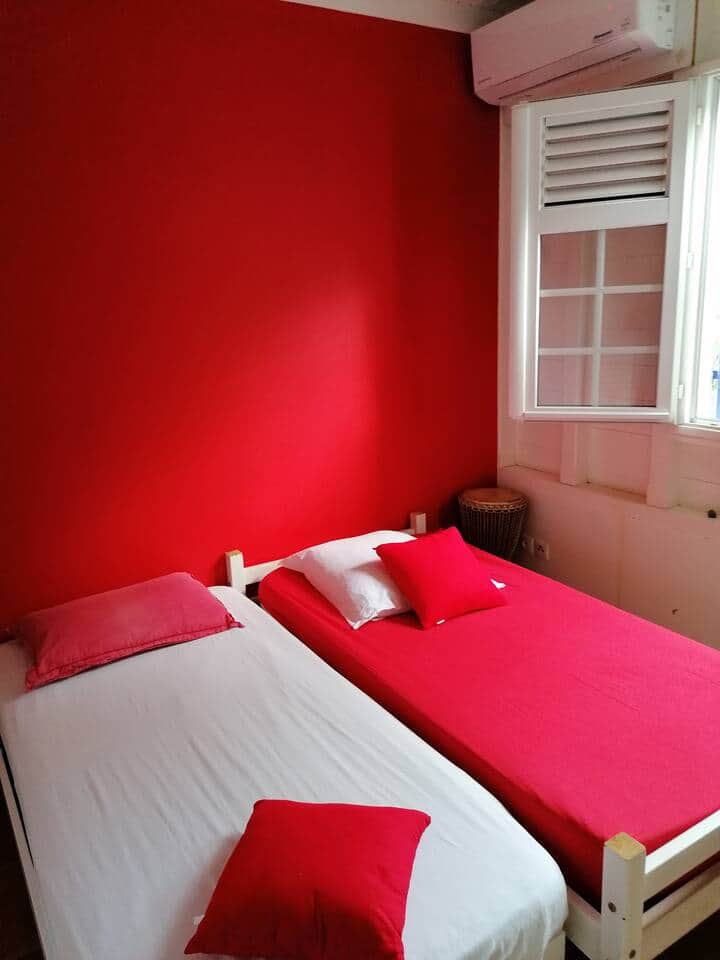 La chambre rouge, composée de deux lits simple, avec une vue sur l'arrière du jardin