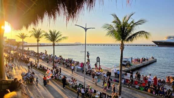 Families and visitors gathering along the waterfront in downtown San Miguel de Cozumel at sunset