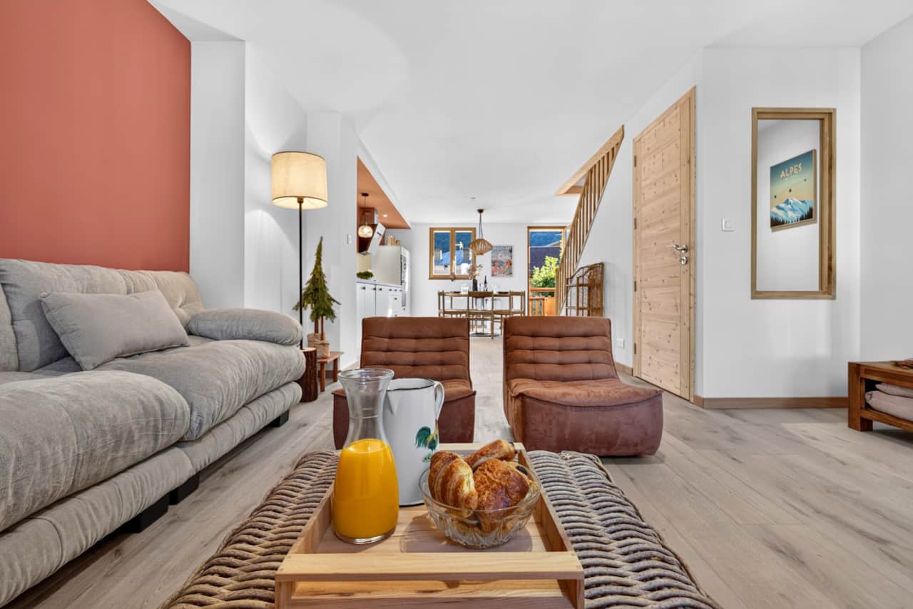 Salon cosy ouvert sur le coin repas, canapé profond et fauteuils en velours.