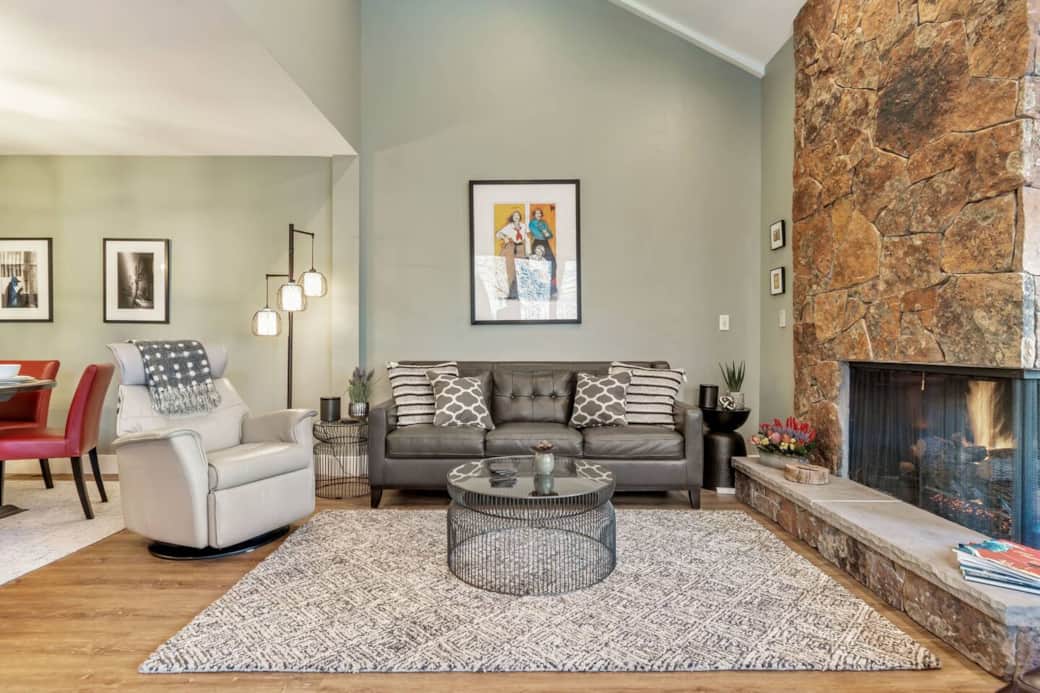 Spacious living and dining room with fireplace, views of the mountains, and hot tub just outside.