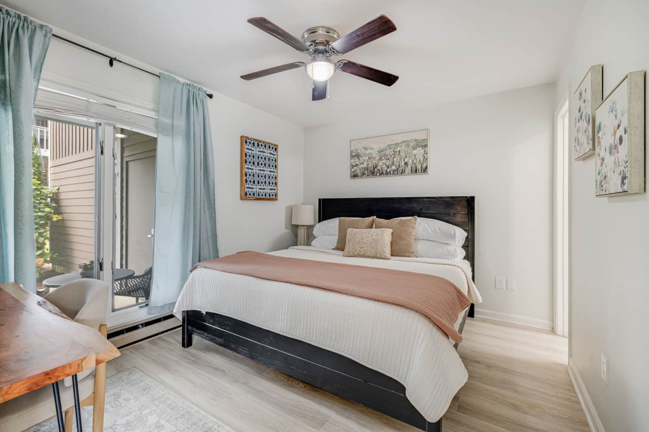 King bedroom with black panel bed and ceiling fan