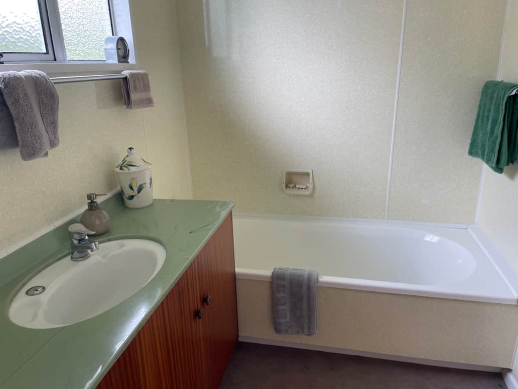 Bathroom 1: 1950's melamine walls and 1970s avocado sink! 1950s bathtub. Separate toilet.