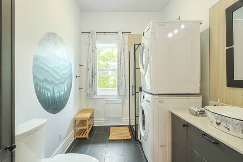 Nouvelle salle de bain élégante avec douche design, laveuse/sécheuse et touche artistique locale