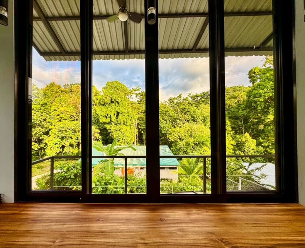 Floor-to-ceiling windows frame the lush greenery