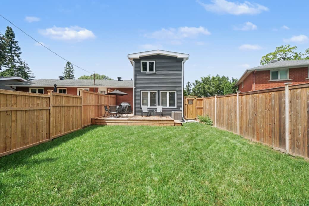 Private fenced backyard with a spacious wood deck and lush green grass, perfect for relaxation Private fenced backyard with a spacious wood deck and lush green grass, perfect for relaxation
