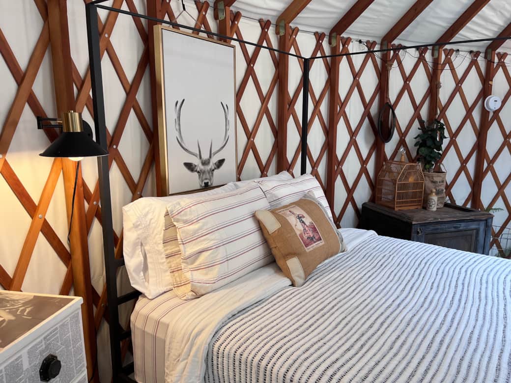 Cozy queen bed inside the handcrafted yurt retreat at The Hollow.