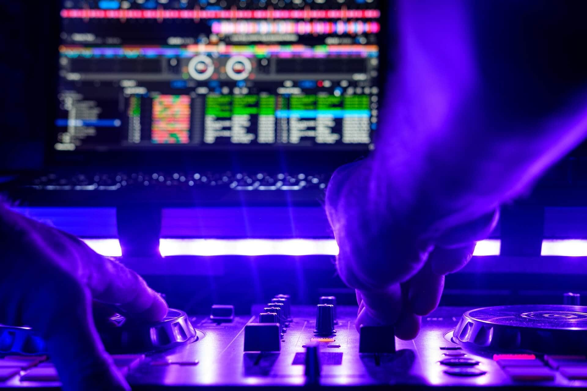 DJ bedient Mischpult mit Laptop bei elektronischer Musikveranstaltung