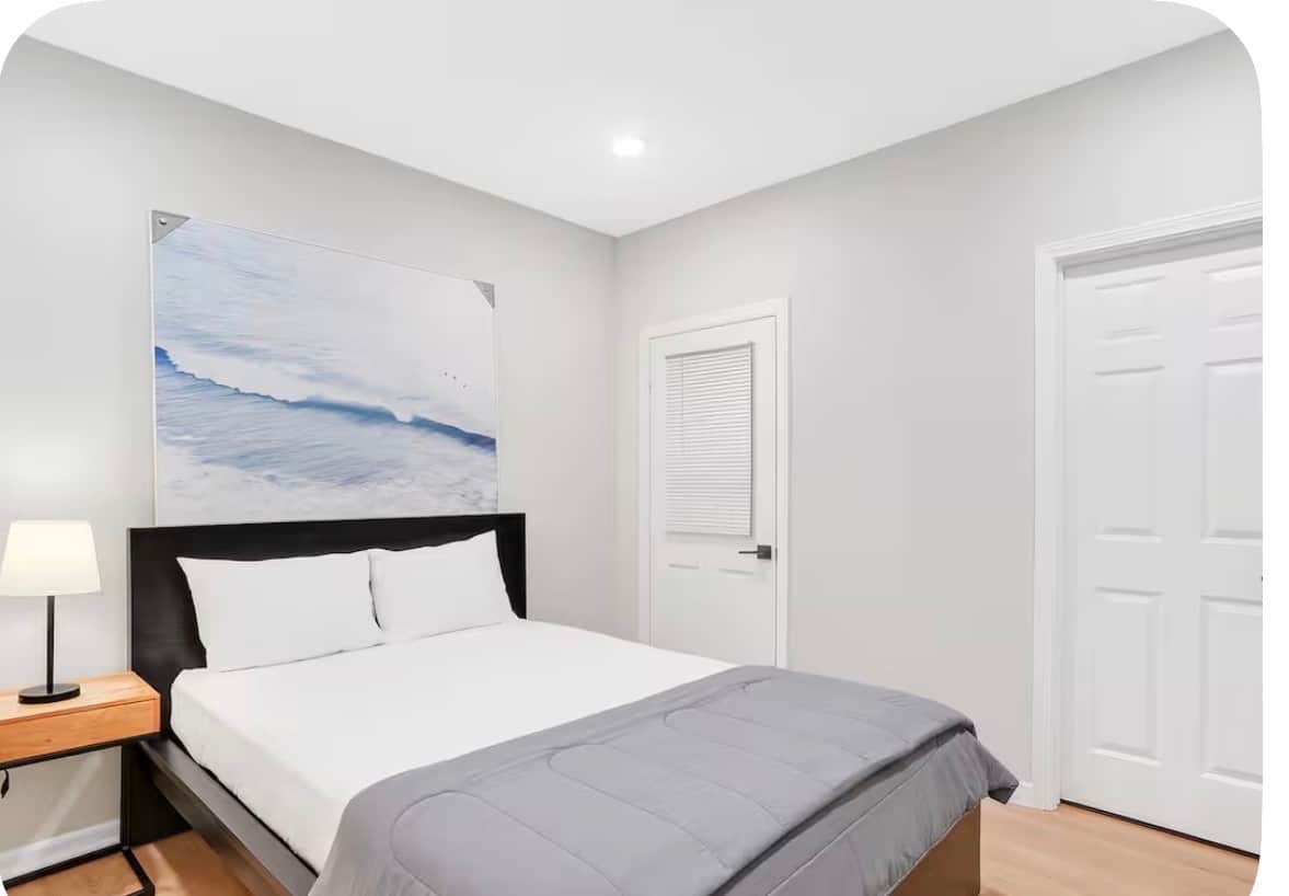 bedroom 1:Relax in this modern bedroom featuring a comfortable queen-size bed, plush white bedding with a black duvet, a large closet for plenty of storage, a flatscreen TV for entertainment, room-darkening curtains, and a bright, stylish design perfect for a restful stay.